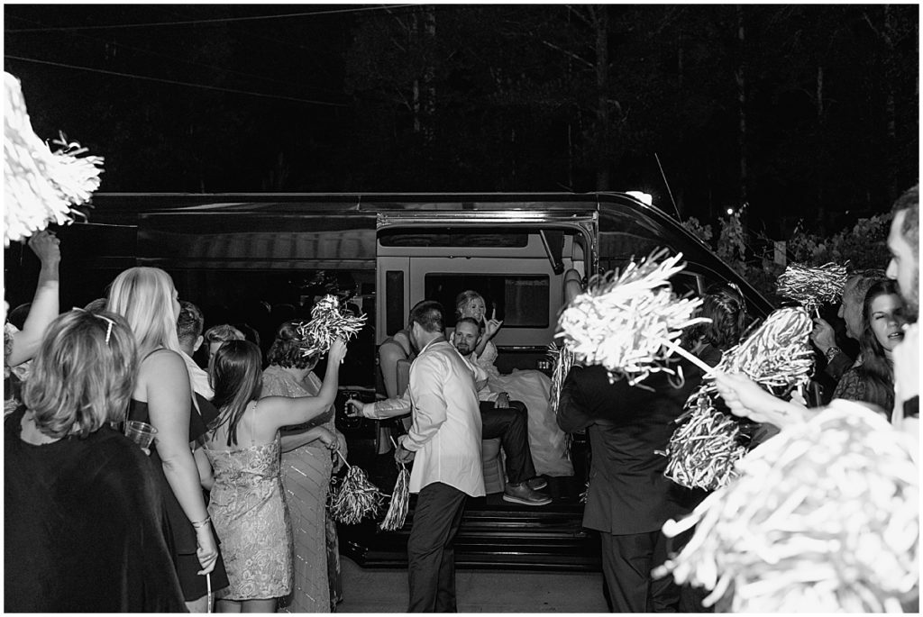 Black and white image of bride and groom exiting their wedding in a van