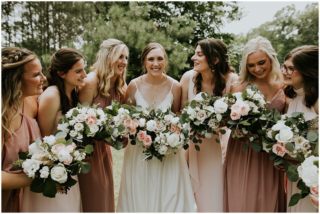 Bride with her bridesmaids all holding bouquets with cream and blush florals