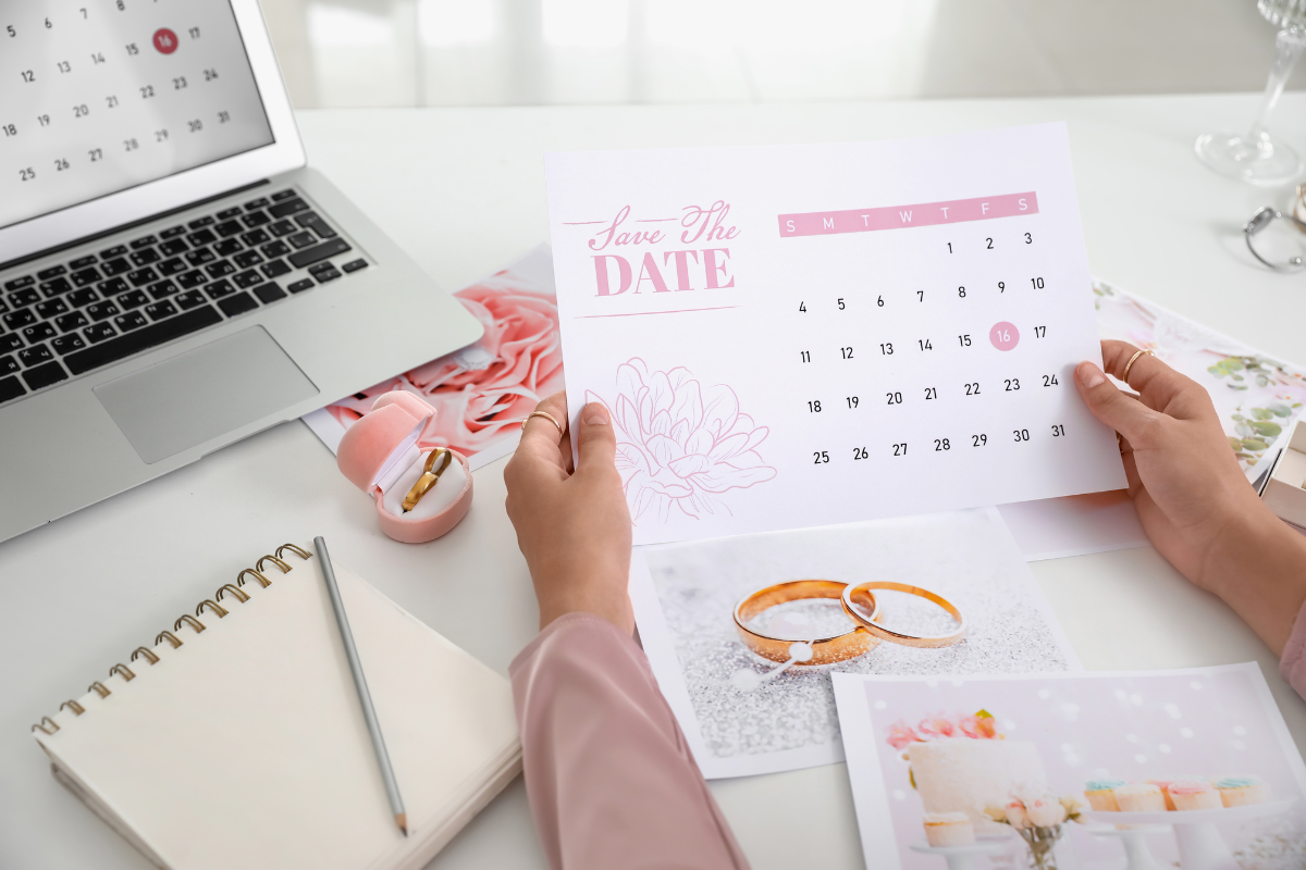 Save the date card and calendar on a desk with wedding pictures