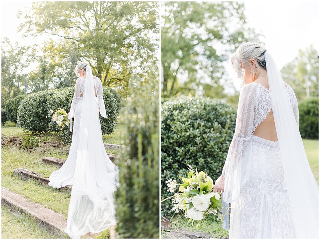Bride in a lace dress with long veil holding a bouquet of white and green florals