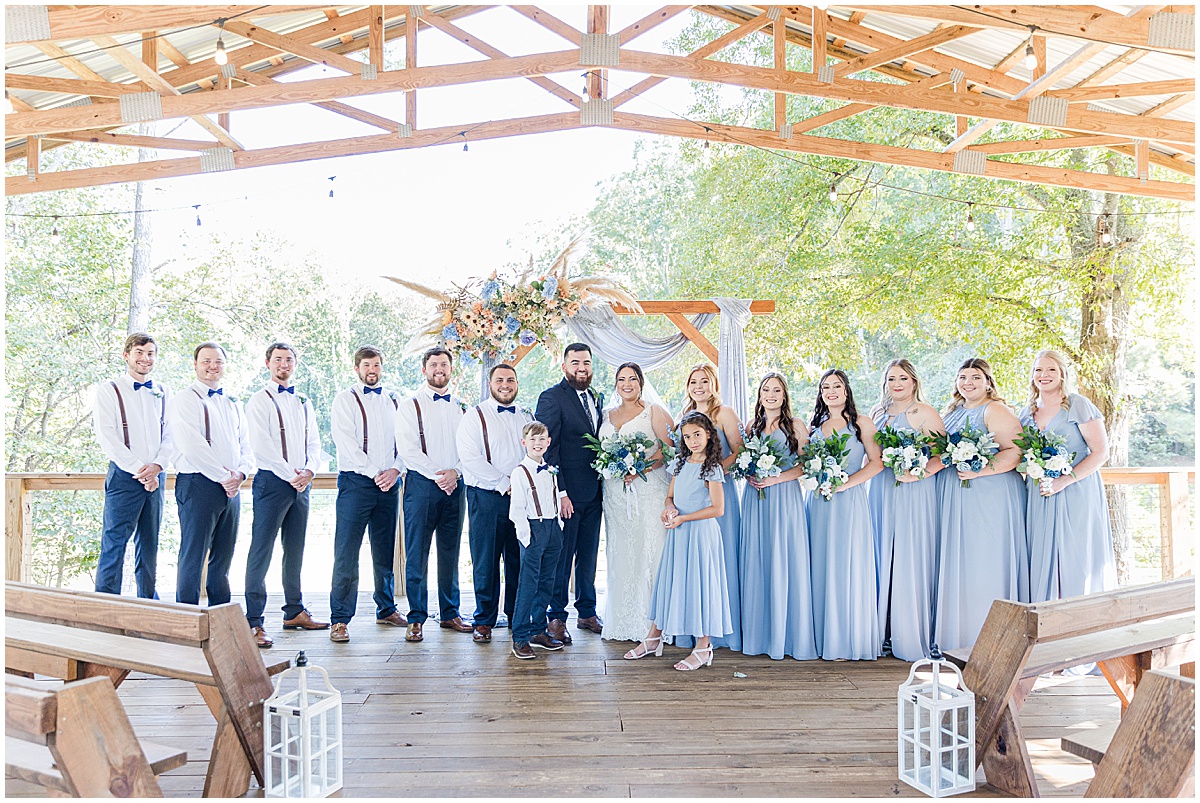 Blue themed wedding ceremony. Wedding Party all dressed in blue. Baby blue dresses for bridesmaids and blue pants and brown suspenders for the groomsmen.