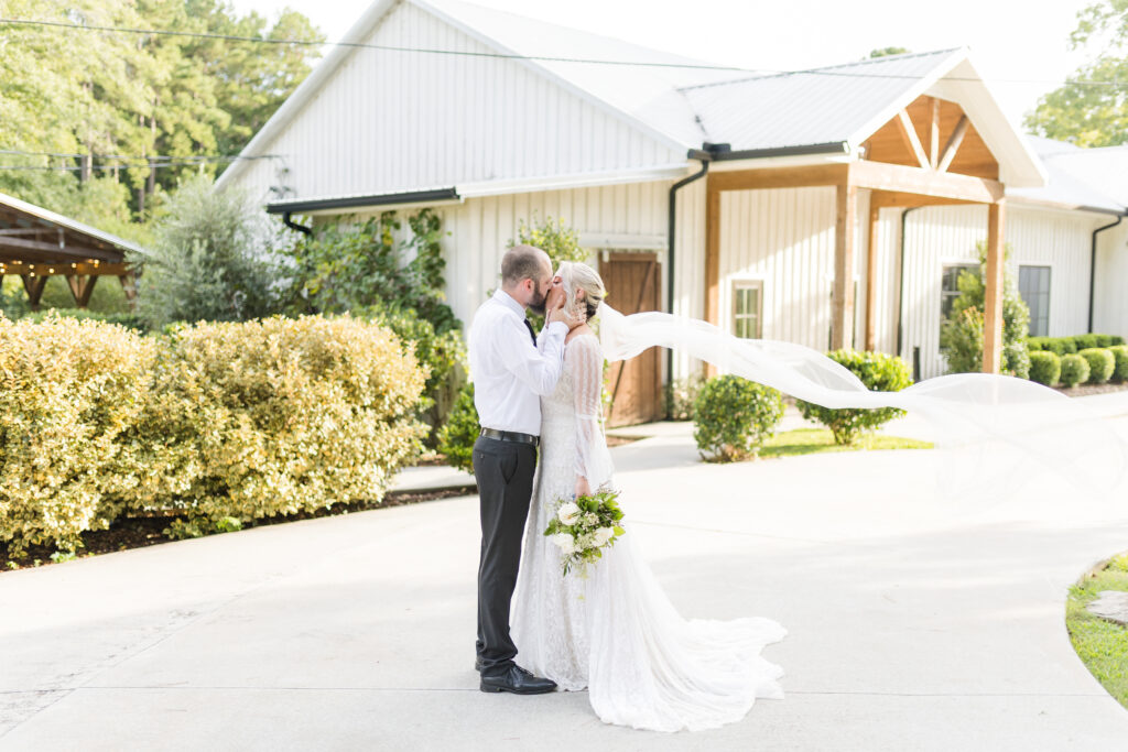 bride and groom kissing outside the main venue at Koury Farms Weddings and events.
