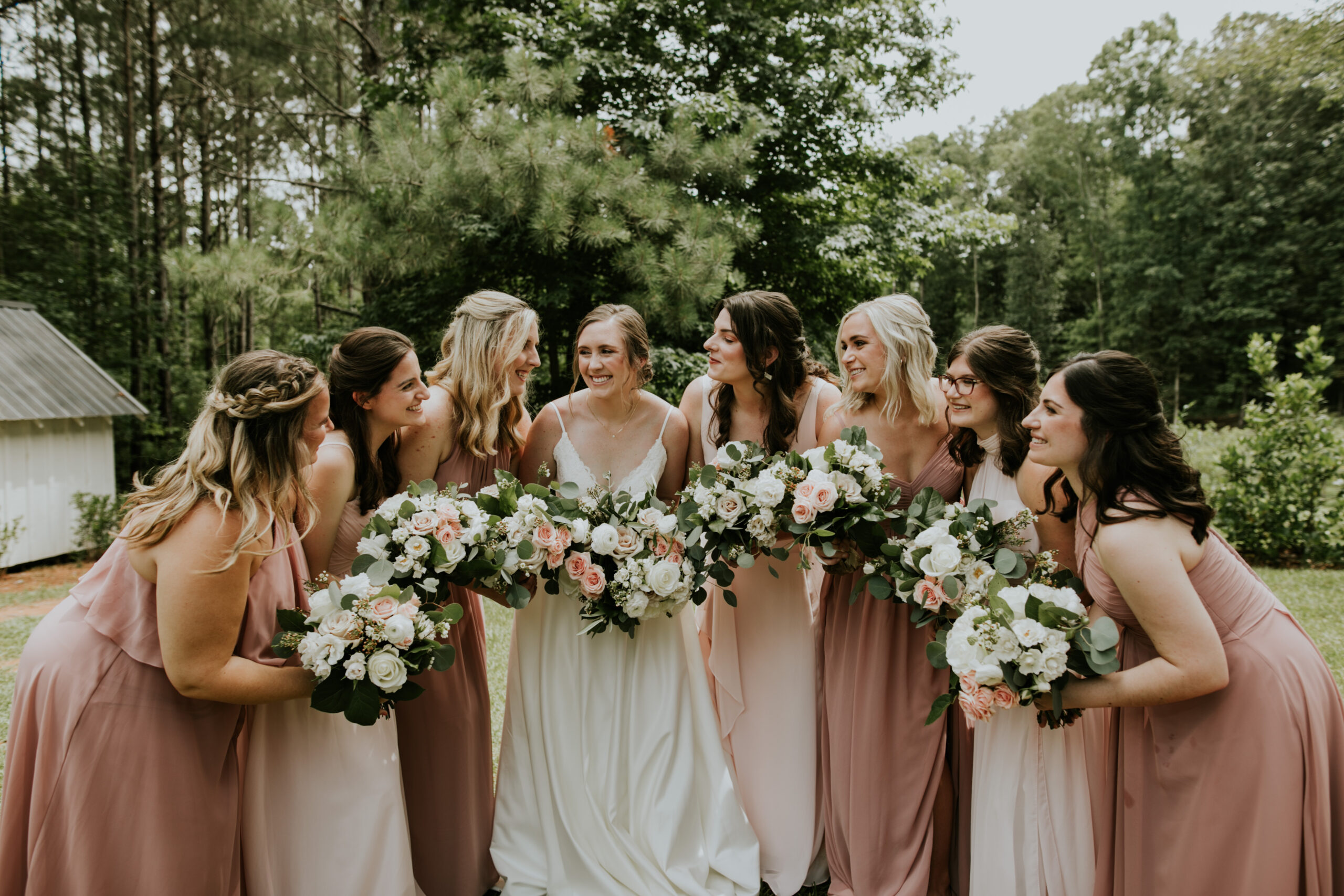 Bride with bridesmaids wearing shades of pink dresses with florals
