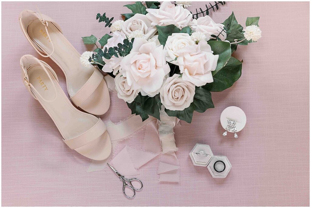 Wedding details flatlay including bouquet, rings, earrings and shoes