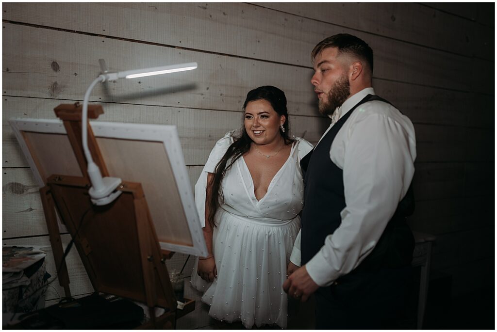 bride and groom admiring the work of the live painter at their wedding