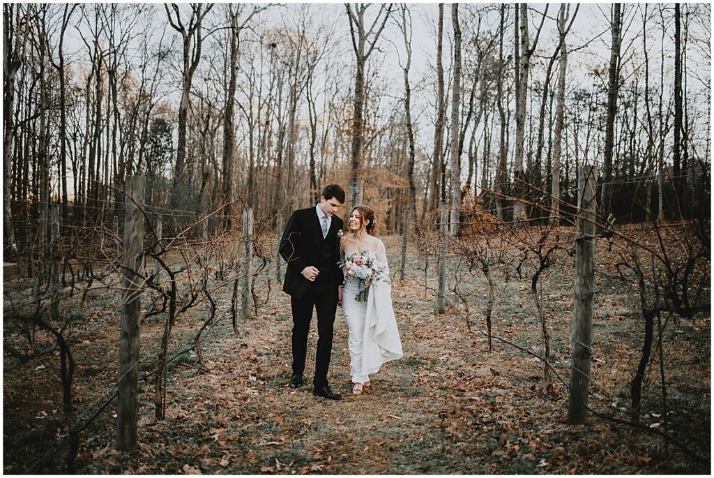 Bride and groom walking amongst the vineyards at winter wedding at Koury Farms