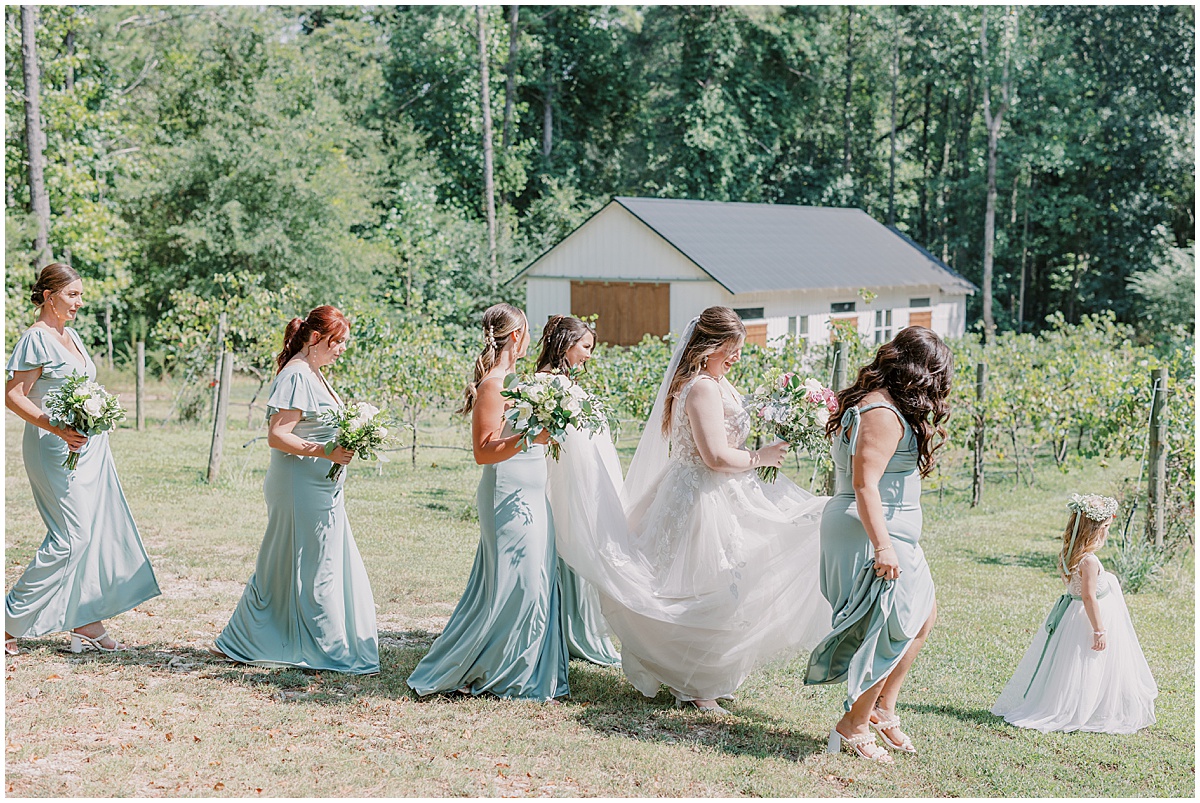 bride walking through vineyards at koury farms with bridesmaids