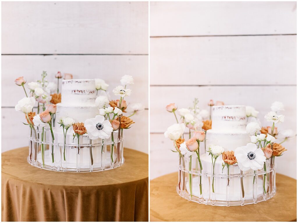 White 3 tiered wedding cake with white and orange florals in acrylic stand