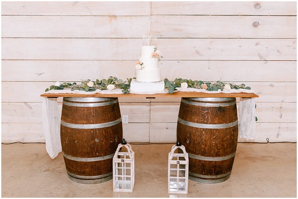 Wedding cake resting on two rustic wooden wine barrels