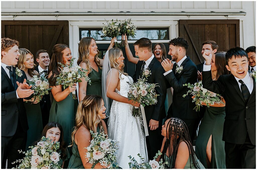 Bride and groom in the middle of wedding party at olive, black and gold wedding