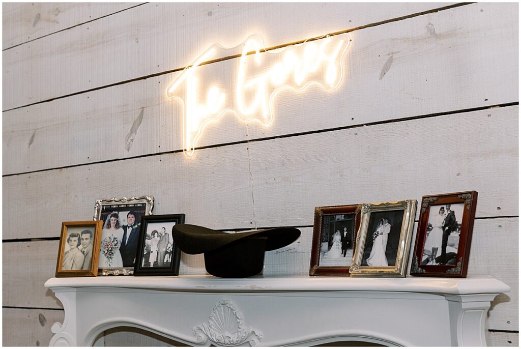 Mantlepiece displaying photos of the couples family with a neon sign lit above it