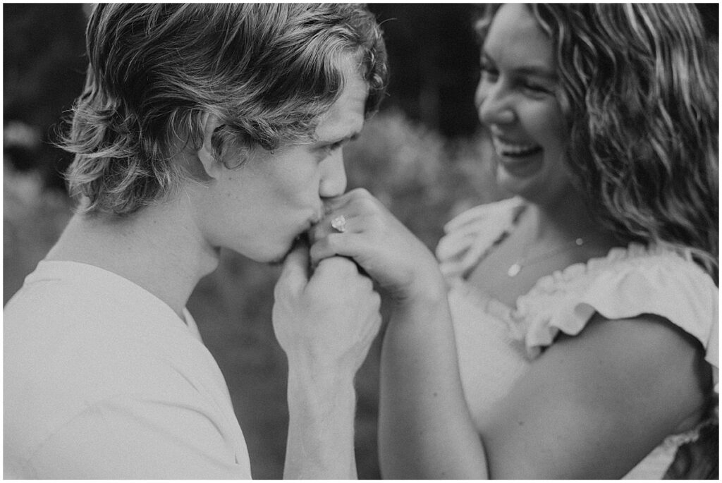 Man kissing hand of women wearing an engagement ring