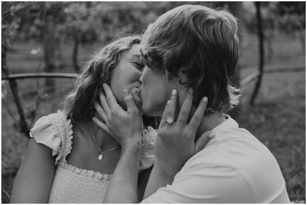 Couple kissing sitting down for vineyard engagement photos