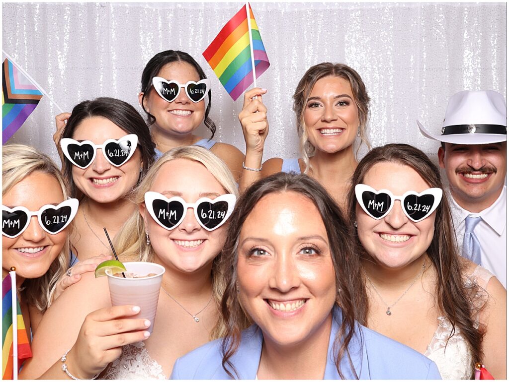 Group of people wearing sunglasses and holding up a flag at Happy Clicks Photo Booth