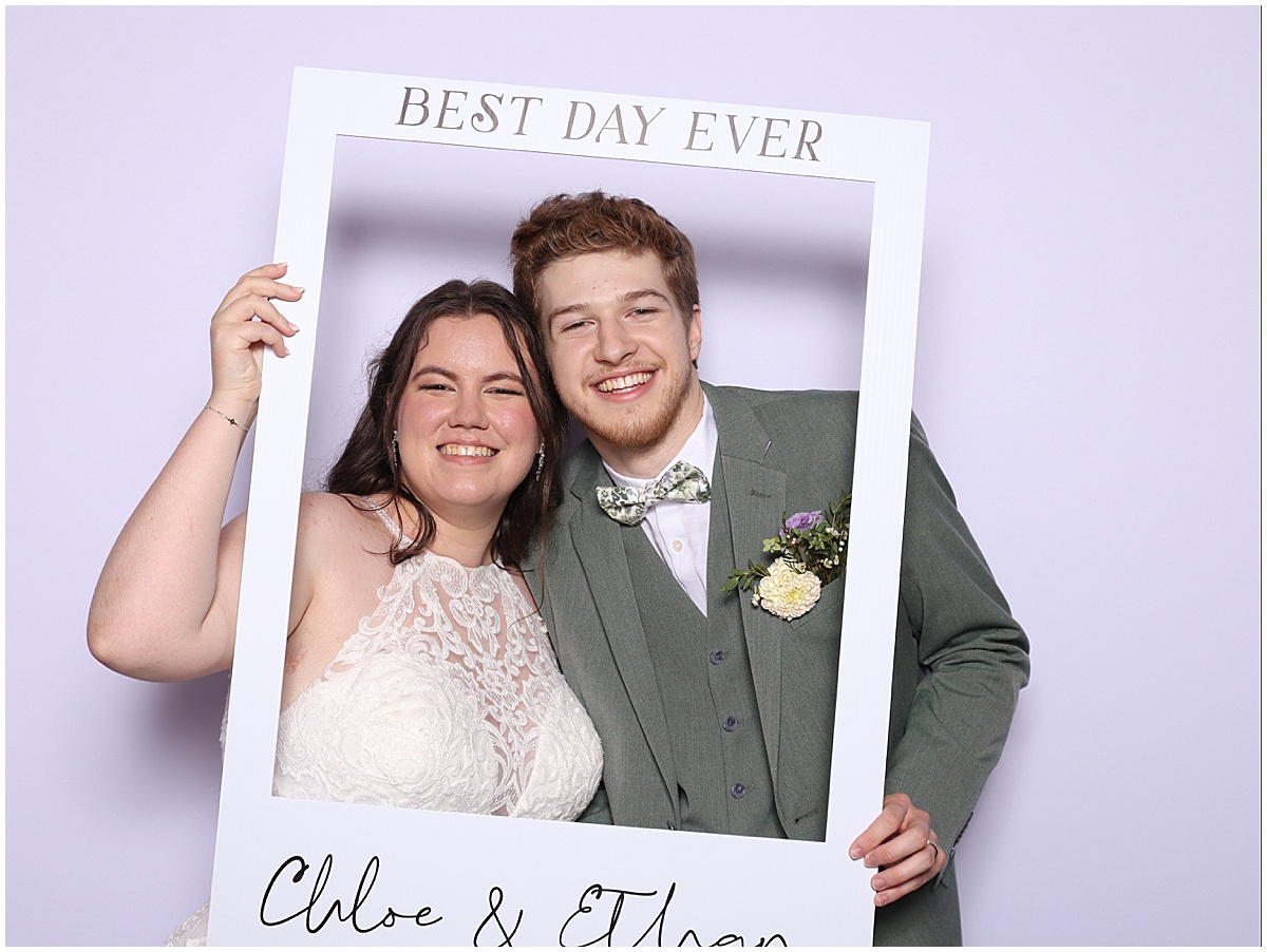 Bride and groom holding a photo frame up at Happy Clicks Photo Booth