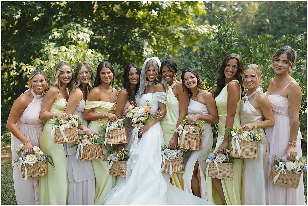 Bride with bridesmaids holding flowers in wooden baskets for elegant pastel wedding at Koury Farms, North Georgia