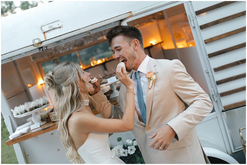 Couple sharing macaroons outside vintage trailer with desserts