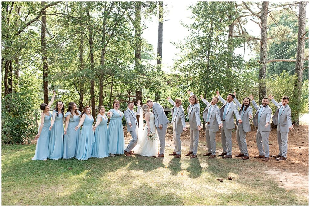 wedding party with bride and groom kissing in the middle