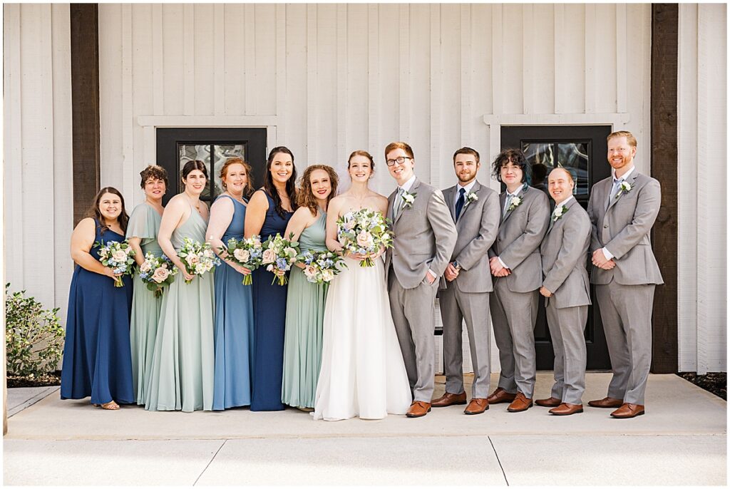 Wedding party standing outside white barn at Koury Farms