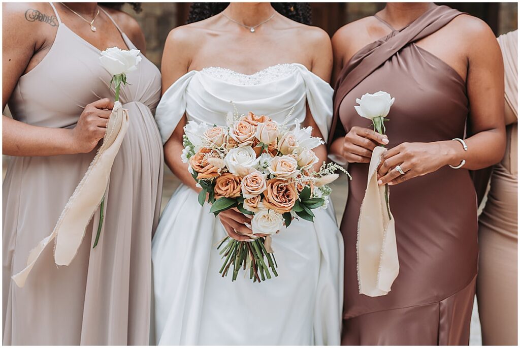 Bridesmaids holding bouquet of peach and blush roses