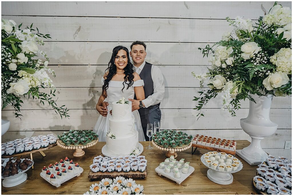 couple standing at dessert table with stunning floral inspiration