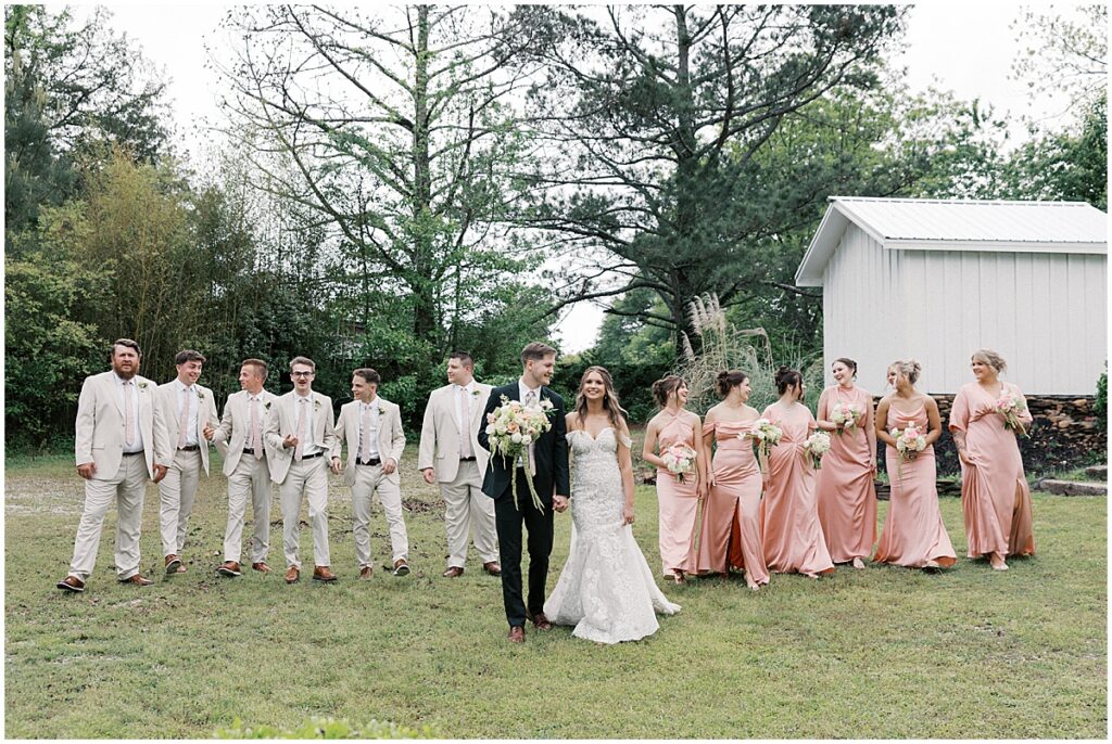 Bride and groom with wedding party wearing tan suits and peach dresses