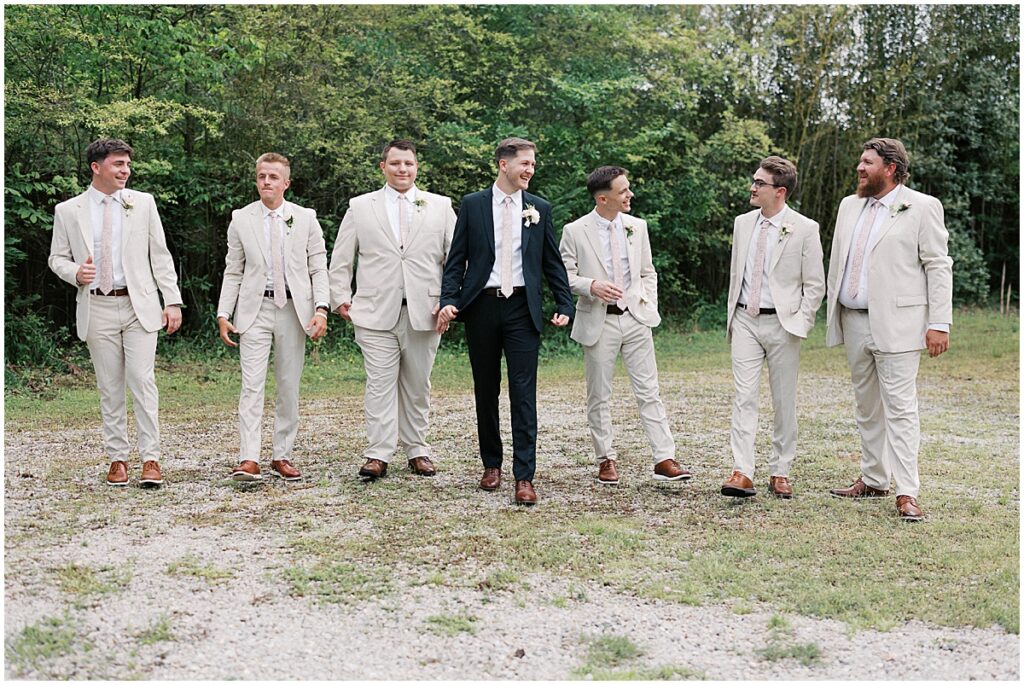 Groom with grooms men, groom wears dark green suit and groomsmen in tan suits