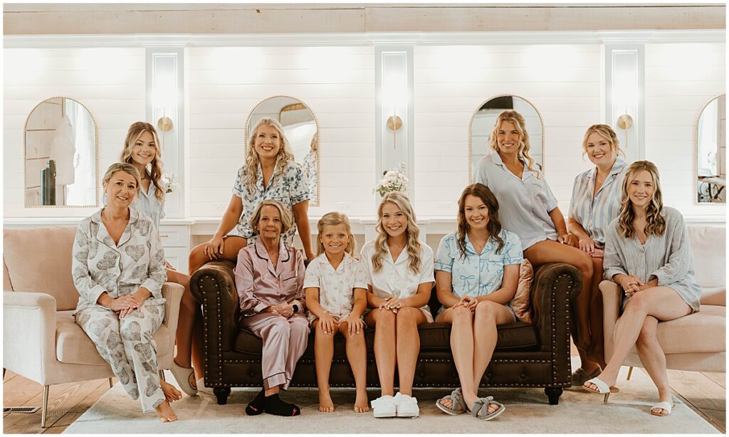 Bride with her bridesmaids, mother and flower girl in the bridal suite at Koury farms sitting on brown couch