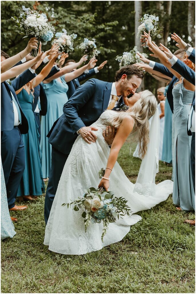 bride and groom kissing under arms of bridal party