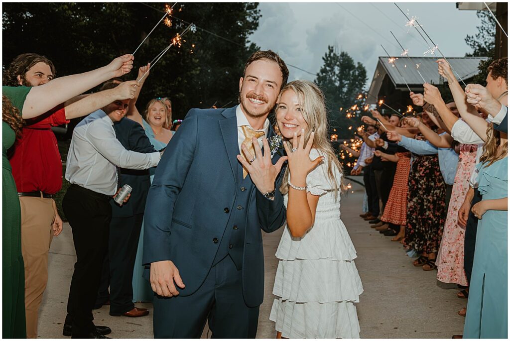 bride and groom at sparkler exit showing wedding rings